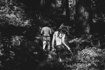 白天两个赤裸上身的人站在森林里的灰度照片